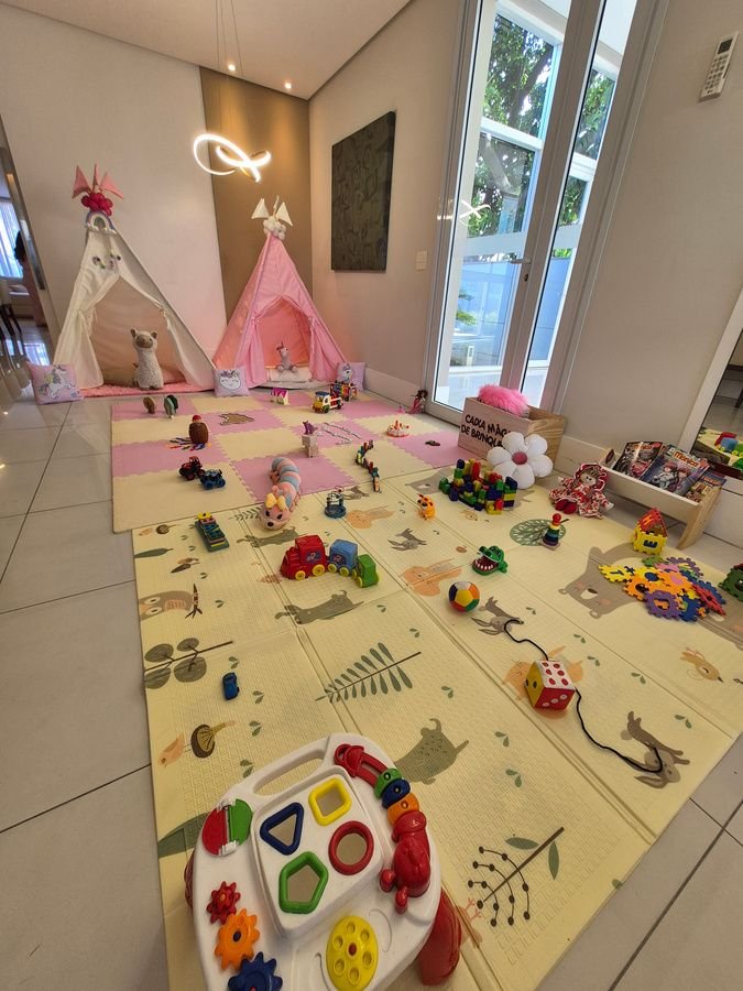 Sala com teepee rosa e tapete de atividades cheio de brinquedos